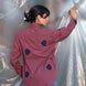 Person wearing a plum shirt with aesthetic navy blue tulip embroidered applique on the shirt against a silver tarp background