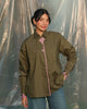 Woman wearing a olive green shirt with pink accents against a plain background