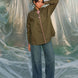 Woman wearing an olive green shirt and blue jeans standing behind a plastic sheet
