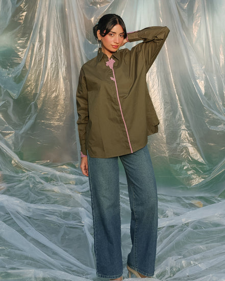 Woman wearing an olive green shirt and blue jeans standing behind a plastic sheet