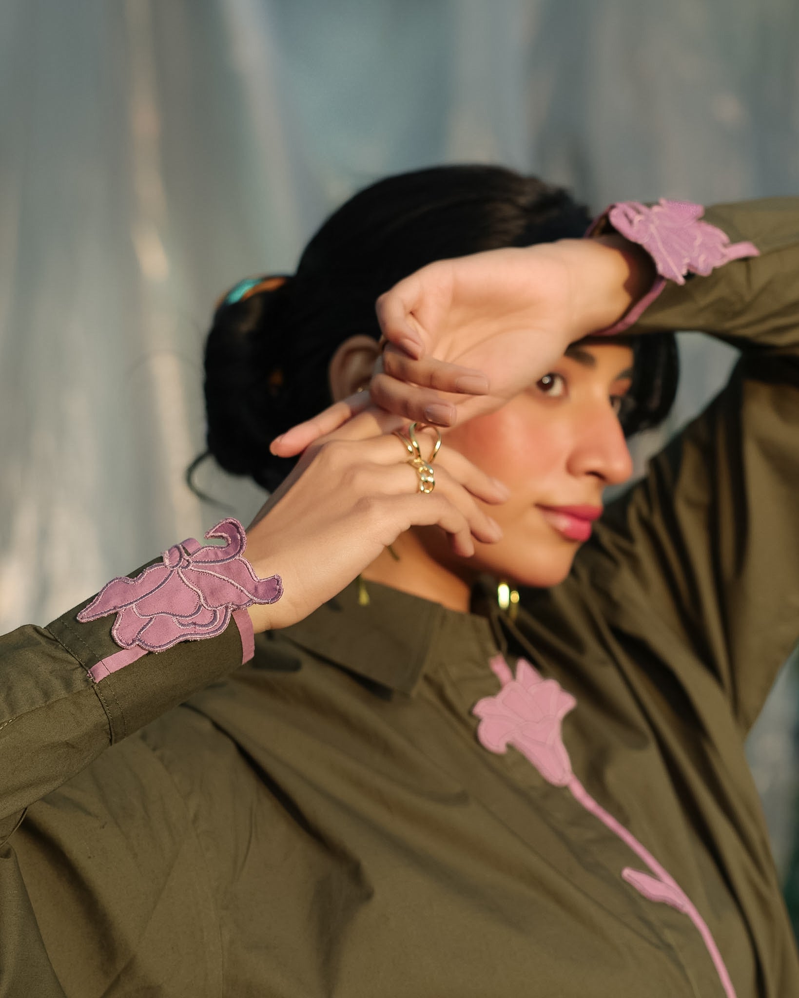 aesthetic shot of a woman wearing an olive green shirt with contrast pink tulip embroidery patches