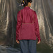 Person wearing a wine silk chanderi shirt and blue pants standing in front of a reflective silver curtain.