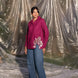 Person wearing a maroon wine shirt with floral embroidery and blue jeans standing inside a large plastic sheet.